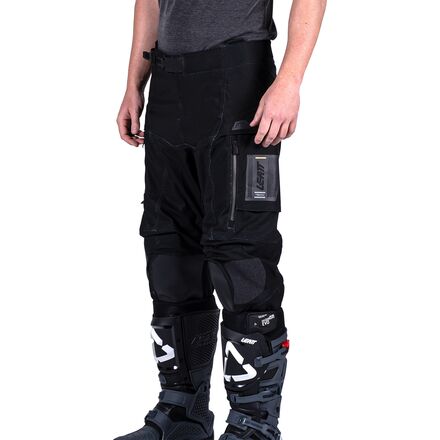 Person wearing black protective pants with knee pads on a white background